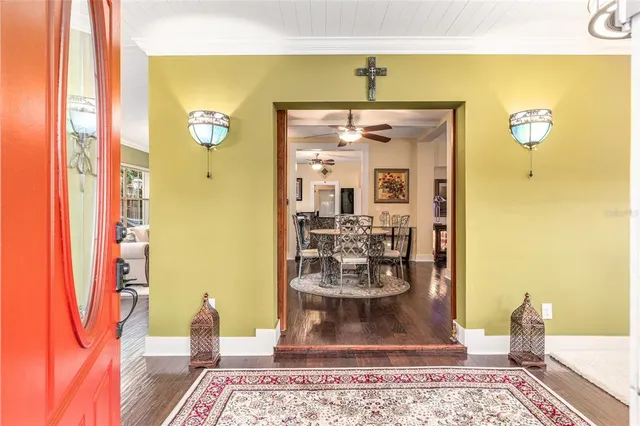 a dining room with wooden floor a chandelier fan a wooden table and chairs