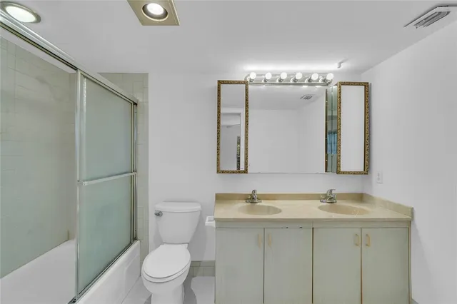 a bathroom with a sink a toilet a mirror and shower