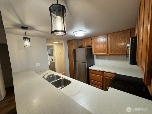 a kitchen with stainless steel appliances kitchen island granite countertop a refrigerator a stove and a sink