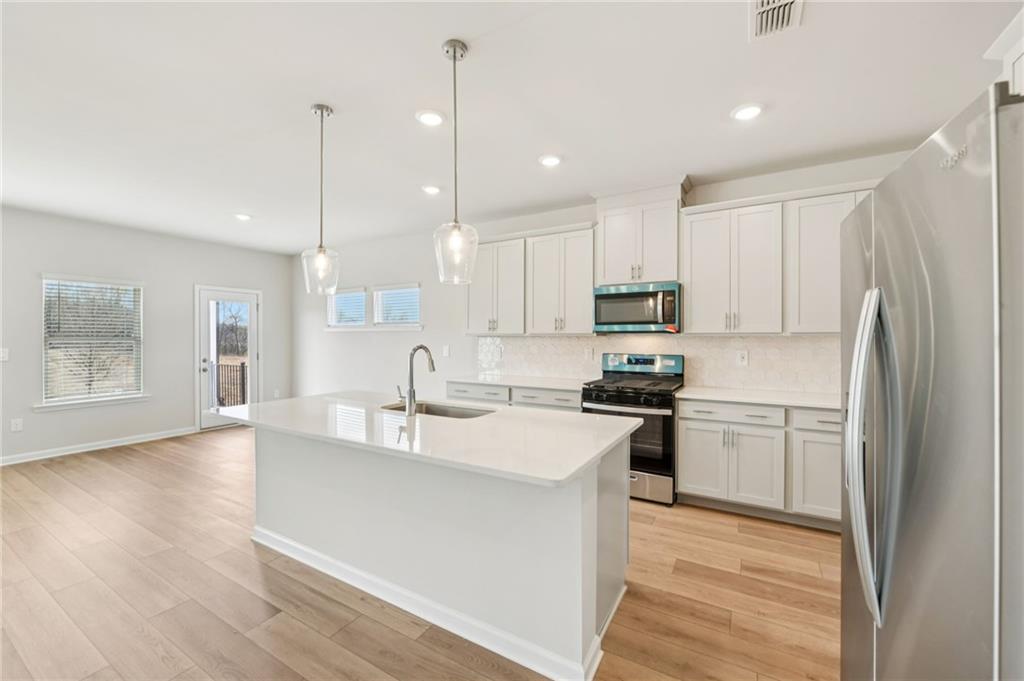 405 Morgan Crk Road Pendergrass, GA 30567 - Photo 16 of 48 a kitchen with stainless steel appliances granite countertop a stove a sink a refrigerator and white cabinets with wooden floor