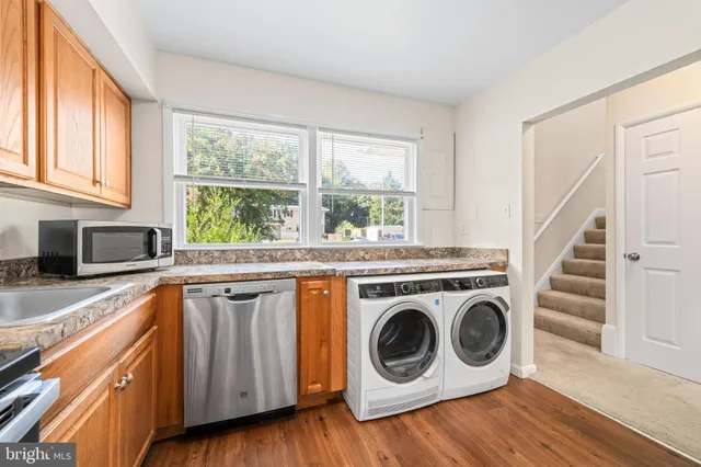 a view of a kitchen with a sink a washer and dryer next to a window