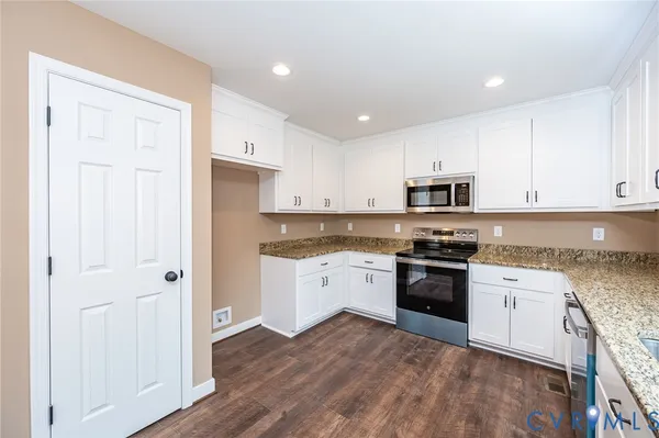 a kitchen with granite countertop white cabinets and white appliances
