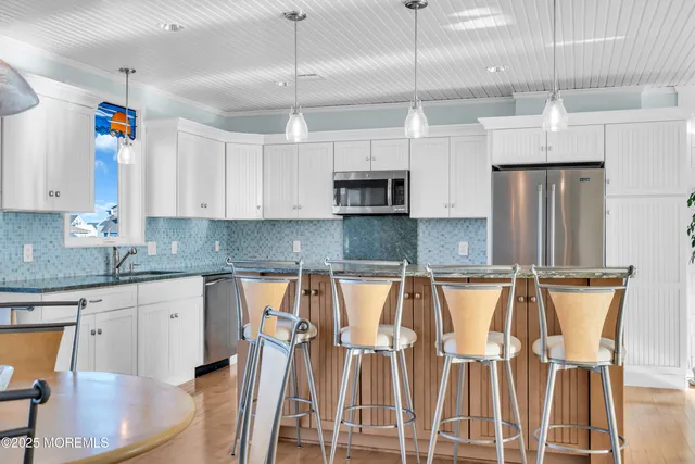 a kitchen with stainless steel appliances granite countertop a refrigerator a stove a sink dishwasher and a refrigerator with wooden floor