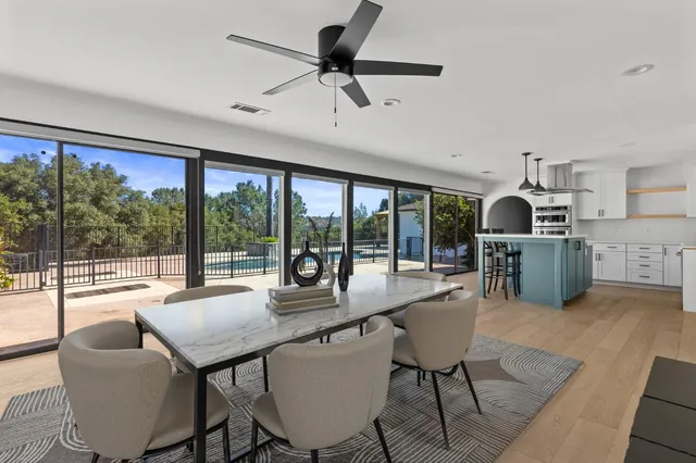 a dining room with furniture large windows and a chandelier