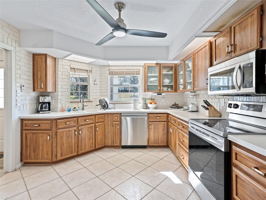 8916 Southwest 8th Street Ocala, FL 34481 - Photo 13 of 40 a large kitchen with stainless steel appliances granite countertop a large stove a sink dishwasher a dining table and chairs with wooden floor