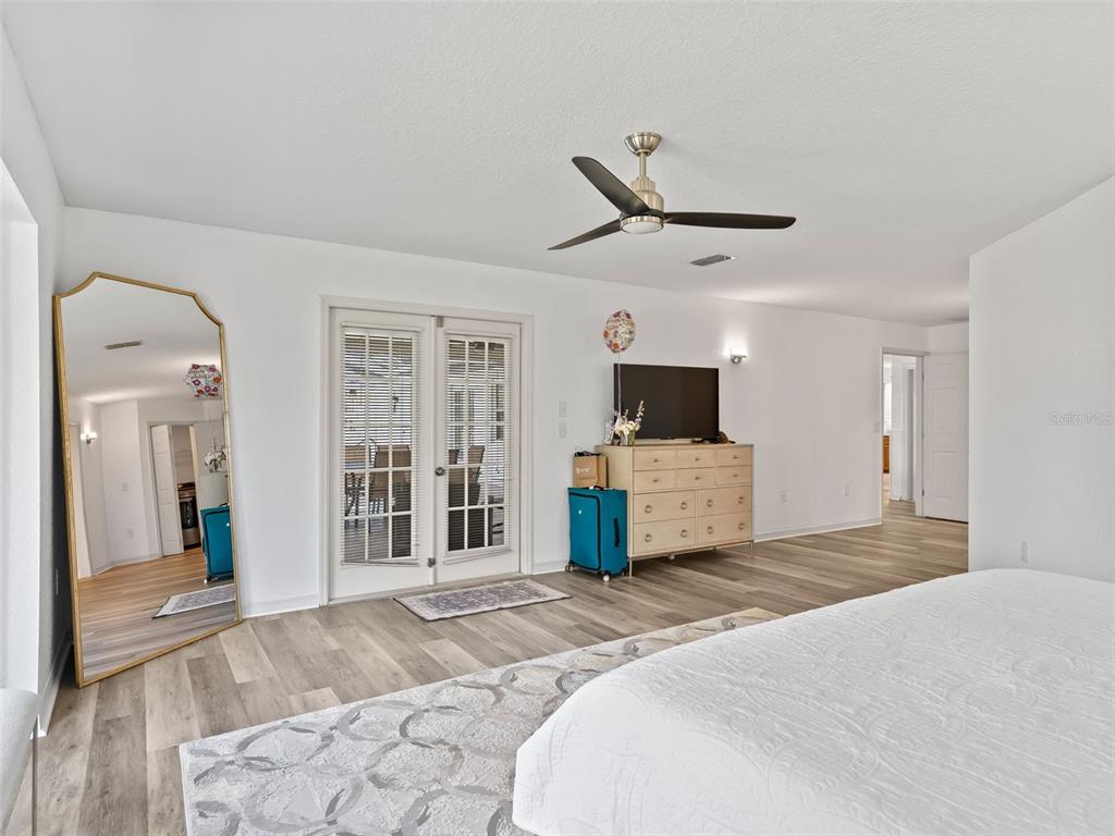 8916 Southwest 8th Street Ocala, FL 34481 - Photo 17 of 40 a bedroom with a large bed a flat tv screen and a chandelier