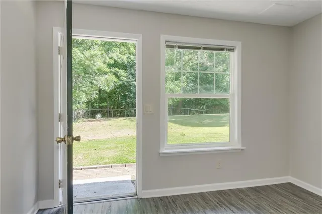 a view of an empty room with wooden floor and a window