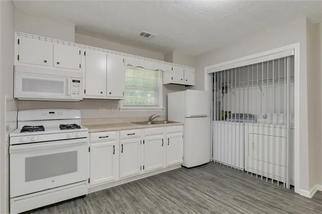 a kitchen with granite countertop white cabinets and white appliances
