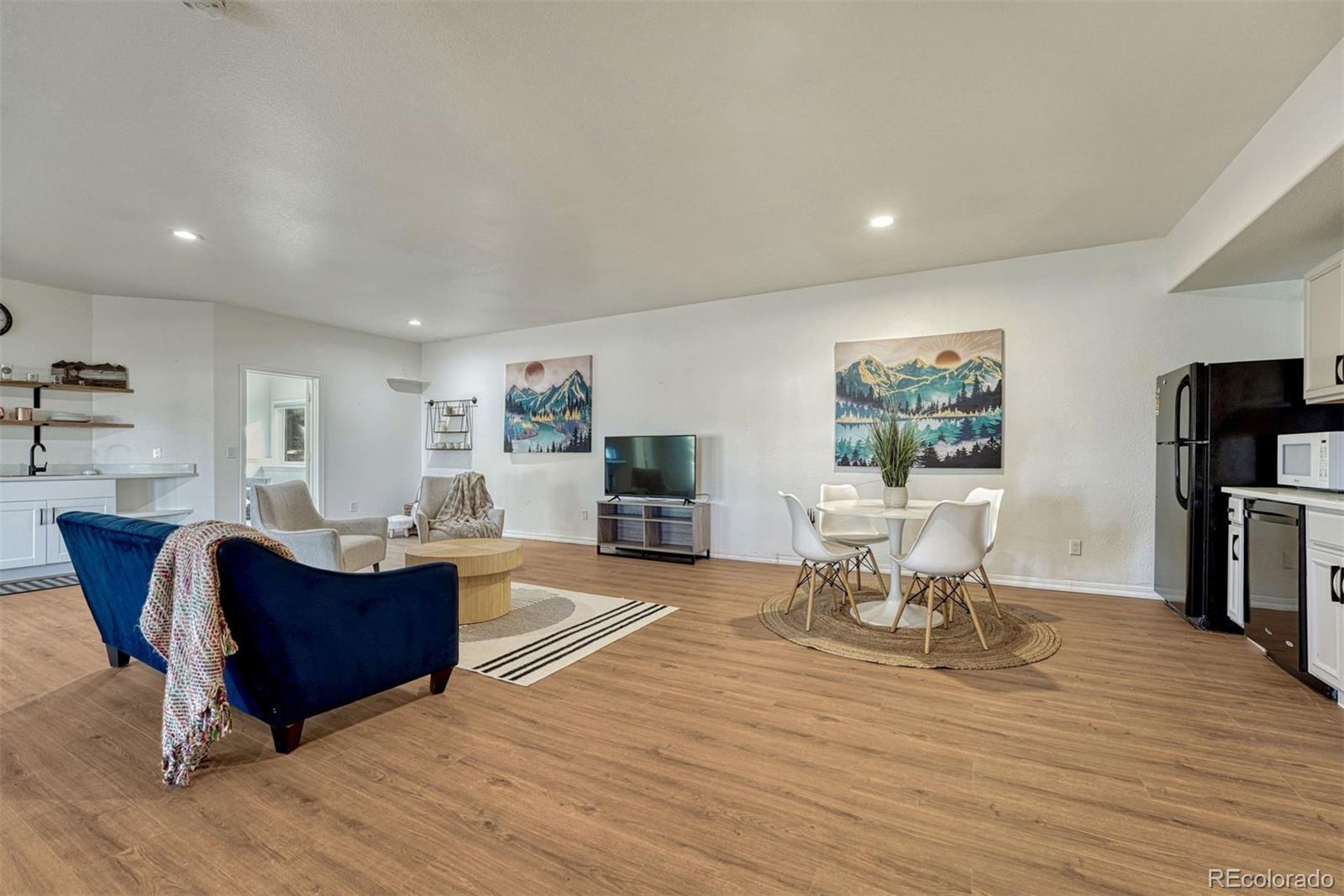 17870 New London Road Monument, CO 80132 - Photo 26 of 44 a living room with furniture a flat screen tv and a dining table with wooden floor