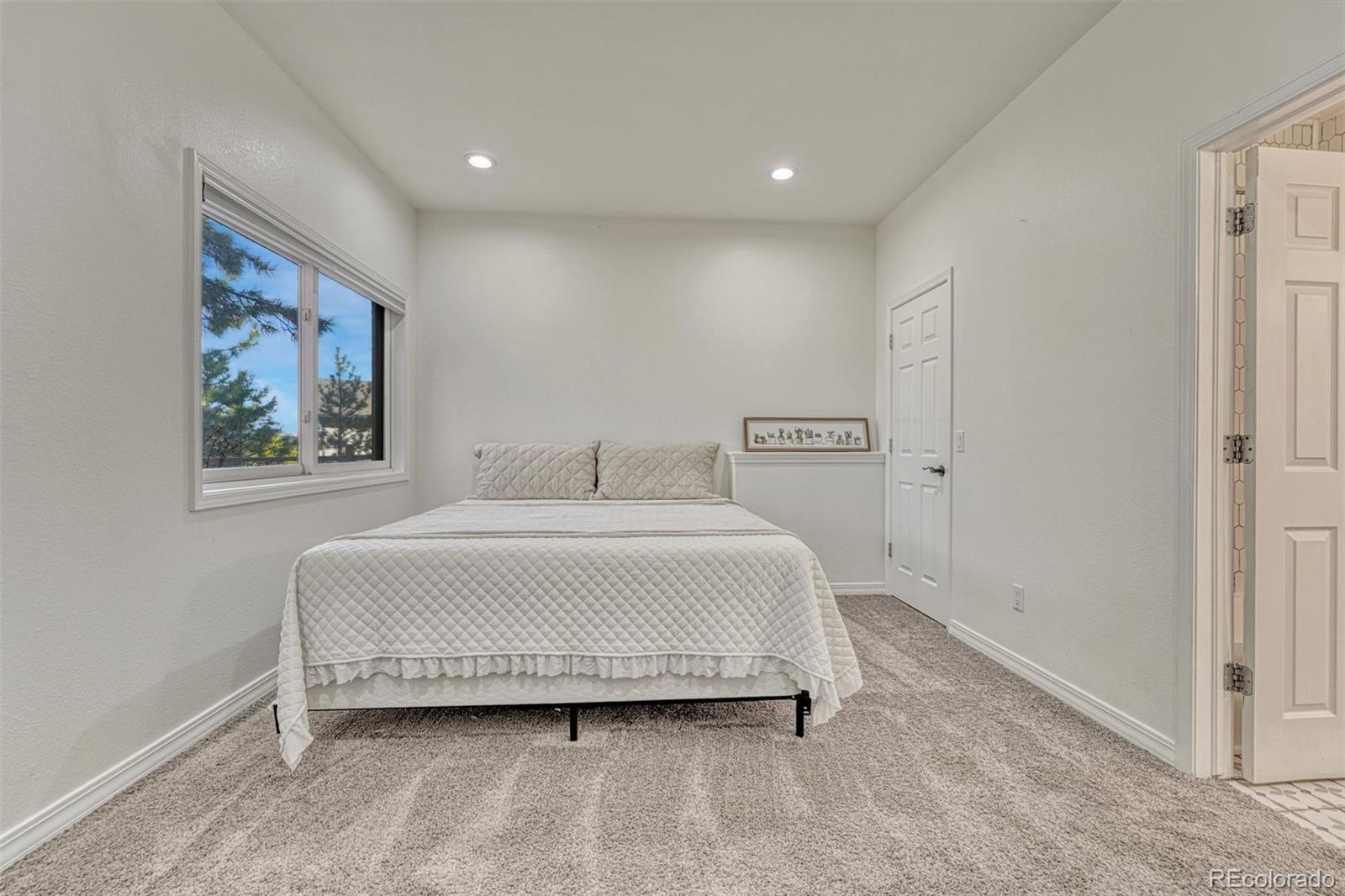 17870 New London Road Monument, CO 80132 - Photo 29 of 44 a spacious bedroom with a bed and a painting on the wall