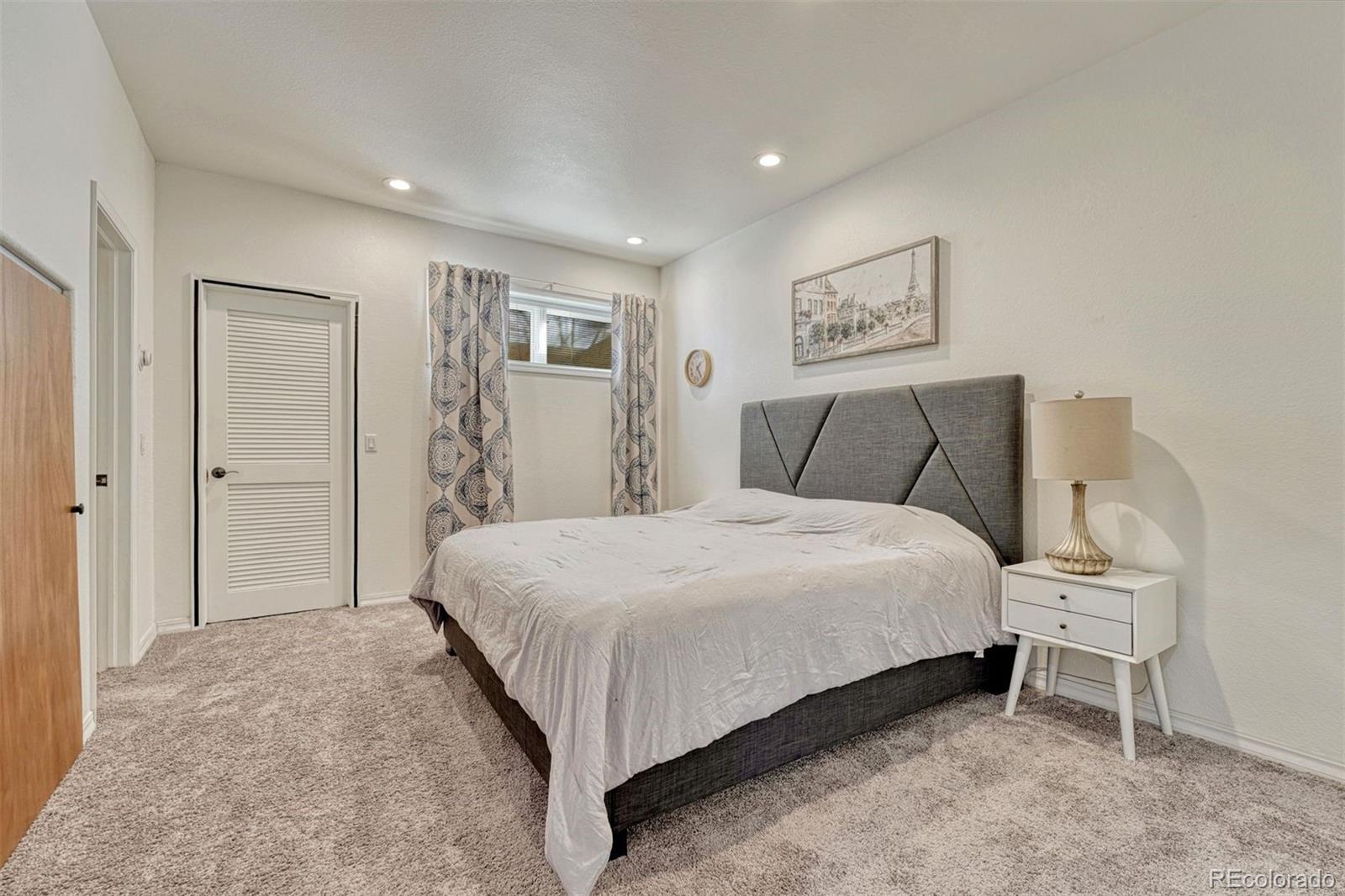17870 New London Road Monument, CO 80132 - Photo 33 of 44 a spacious bedroom with a bed and a lamp