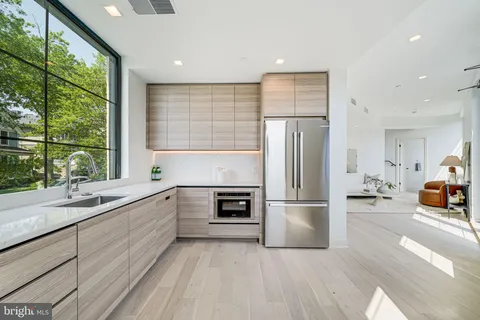 a kitchen with stainless steel appliances granite countertop a refrigerator a stove and a sink with large window