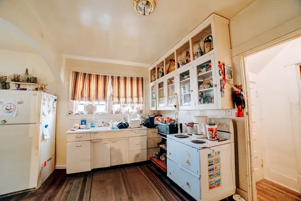a kitchen with a white stove top oven sink and white cabinets with wooden floor