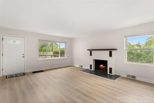 an empty room with windows and fireplace