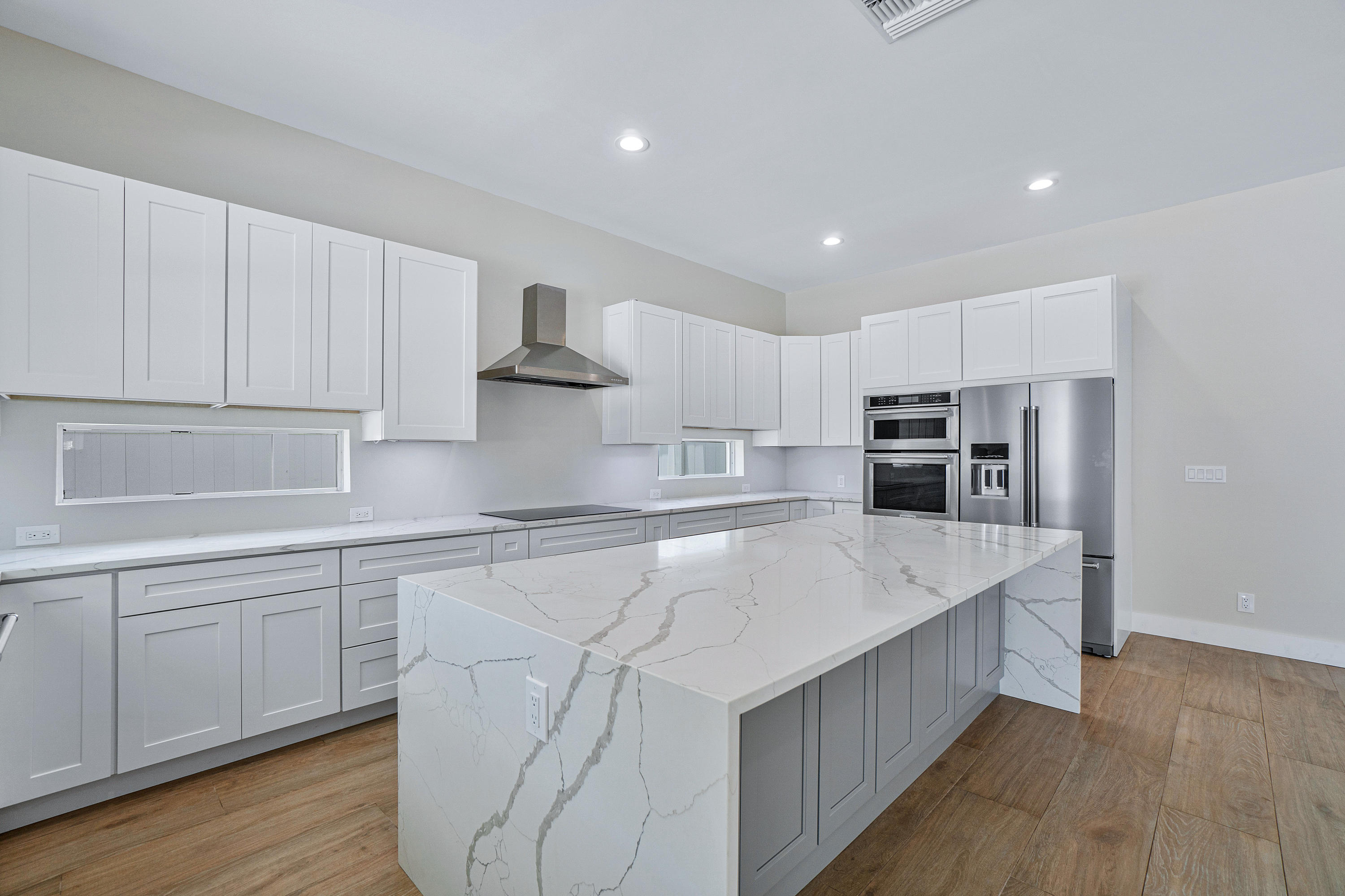 132 Southwest 7th Terrace Boca Raton, FL 33486 - Photo 7 of 39 a kitchen with stainless steel appliances a sink dishwasher a refrigerator and white cabinets with wooden floor