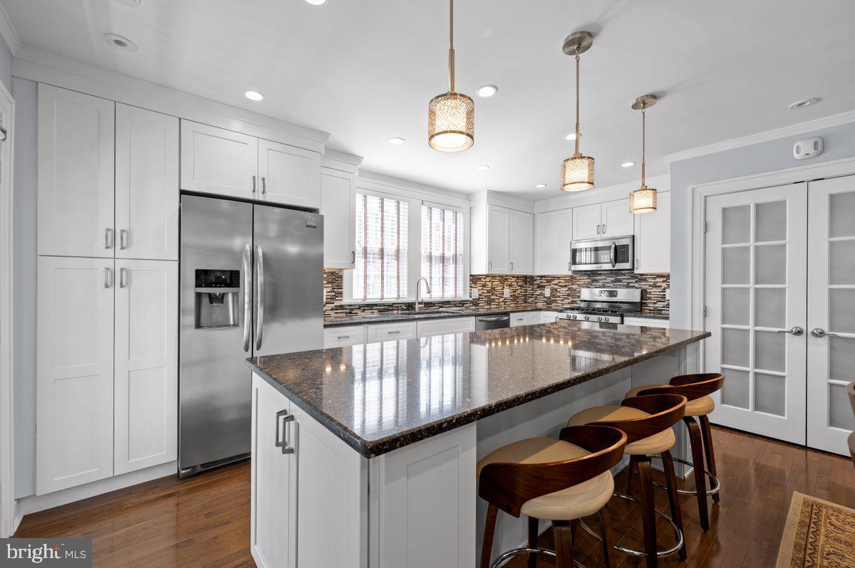 627 Kenilworth Road Ardmore, PA 19003 - Photo 3 of 11 a kitchen with stainless steel appliances granite countertop a sink a stove a refrigerator cabinets and wooden floor