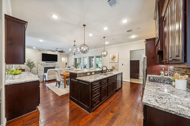 a large kitchen with stainless steel appliances granite countertop a stove and a view of living room