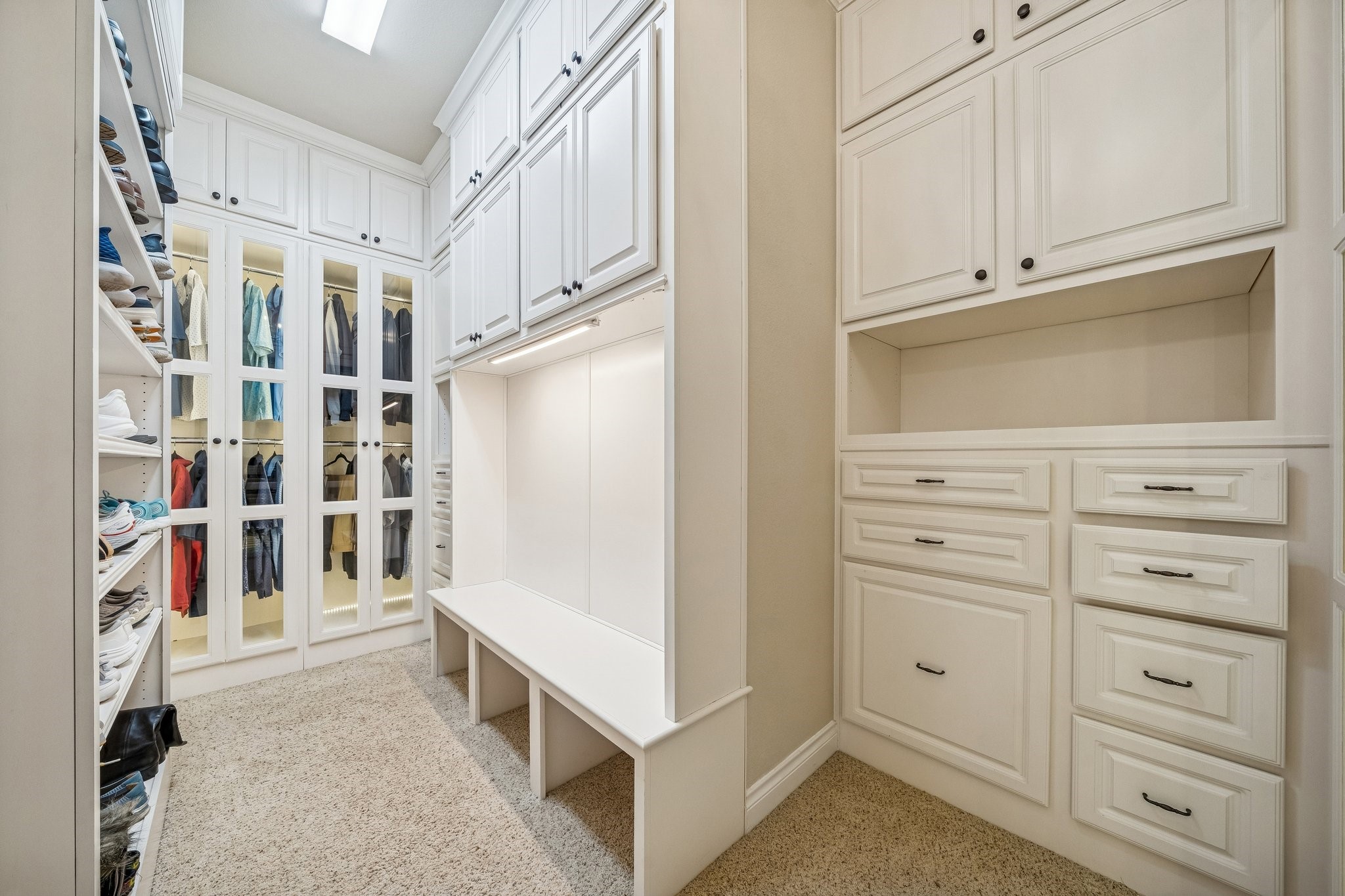 306 Kotar Court Spring, TX 77388 - Photo 23 of 50 Custom lighted closet w/ built-in shelving & cabinets, a sitting bench & glass doors.
