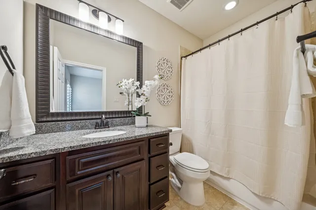 a bathroom with a granite countertop sink toilet and a mirror