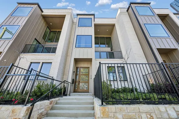 a view of a brick house with a large windows stairs and potted plants