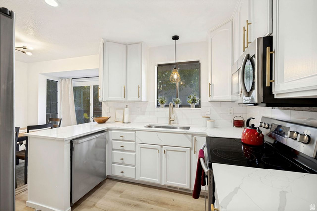 1723 Albury Road Sandy, UT 84092 - Photo 3 of 23 Modern kitchen featuring white cabinetry with gold-tone hardware, white countertops, stainless steel appliances, and wood-finish flooring