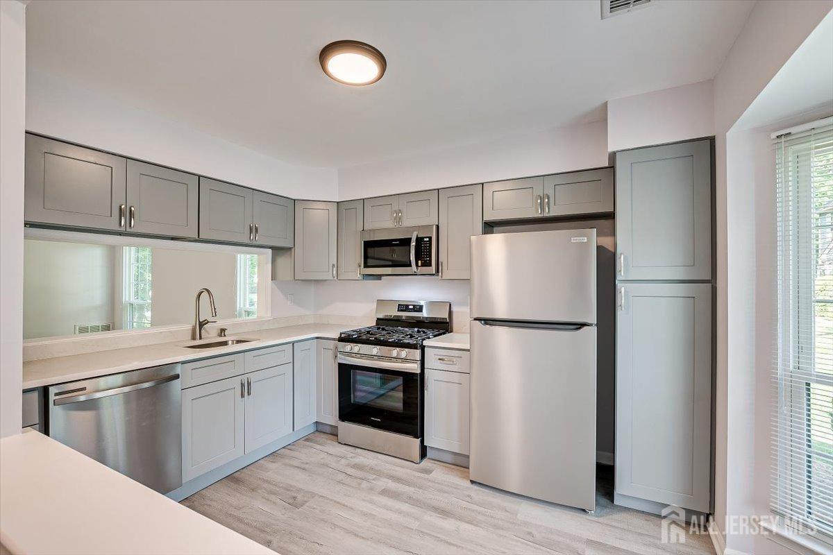 706 Maplecrest Road Edison, NJ 08820 - Photo 12 of 34 a kitchen with a sink a refrigerator and white cabinets