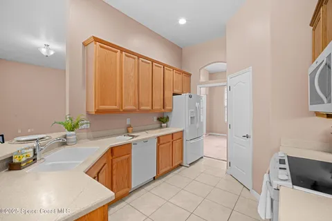 a large white kitchen with a granite countertop sink and a refrigerator