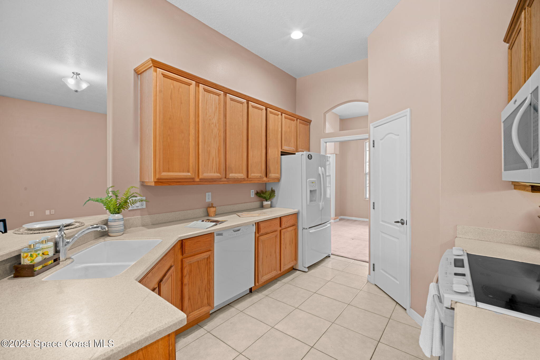 7635 Windover Way Titusville, FL 32780 - Photo 14 of 36 a large white kitchen with a granite countertop sink and a refrigerator