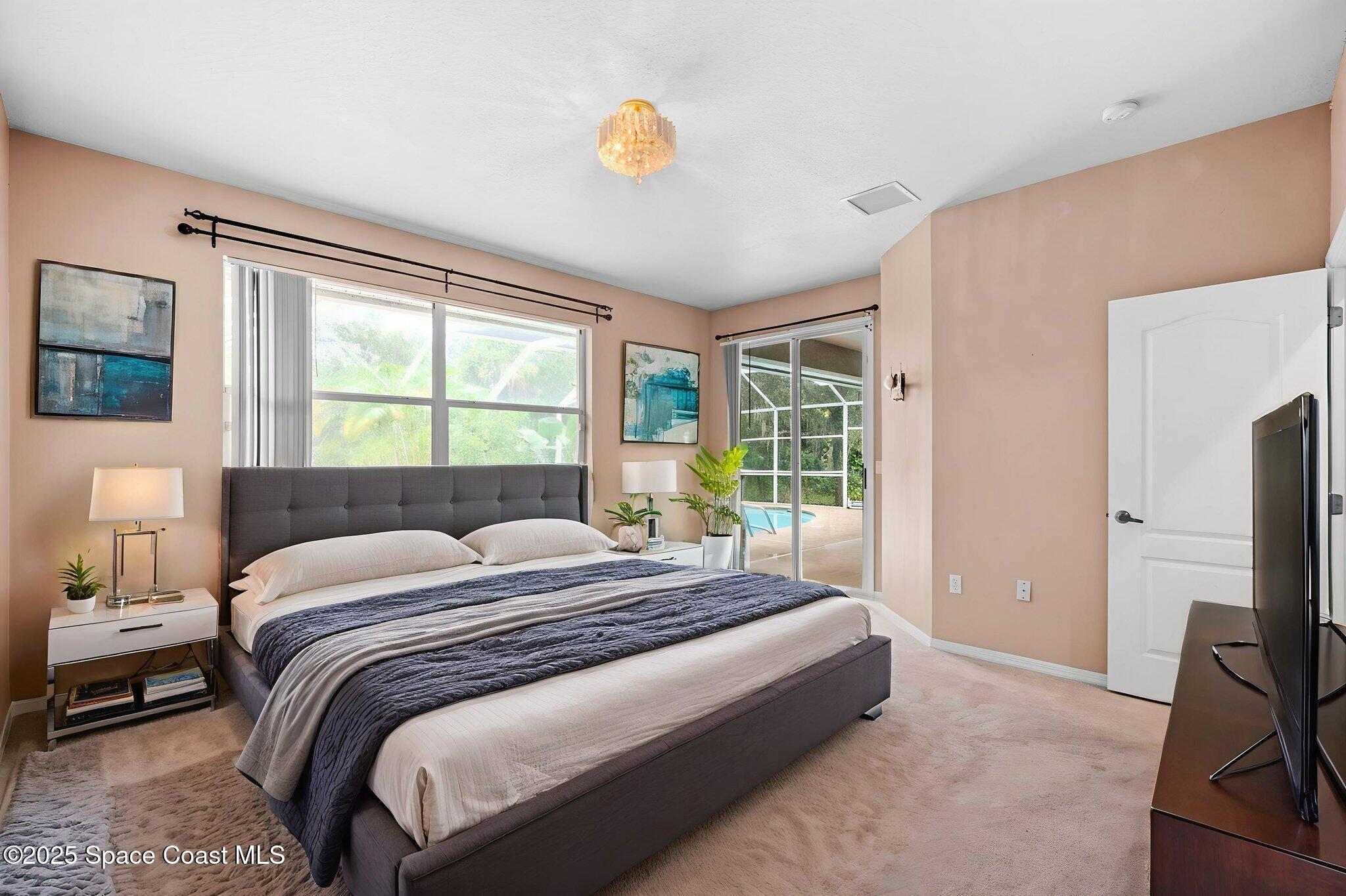 7635 Windover Way Titusville, FL 32780 - Photo 19 of 36 a bedroom with a bed flat screen tv and a large window