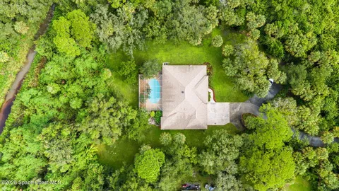 an aerial view of a house with a yard and large trees