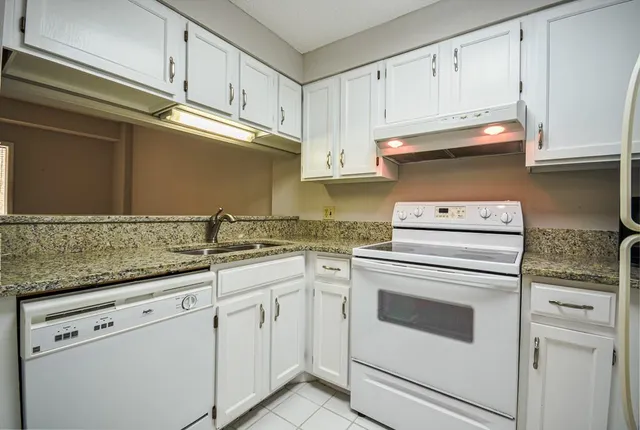 a kitchen with granite countertop white cabinets and white appliances