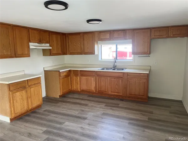 a kitchen with granite countertop a sink cabinets and wooden floor