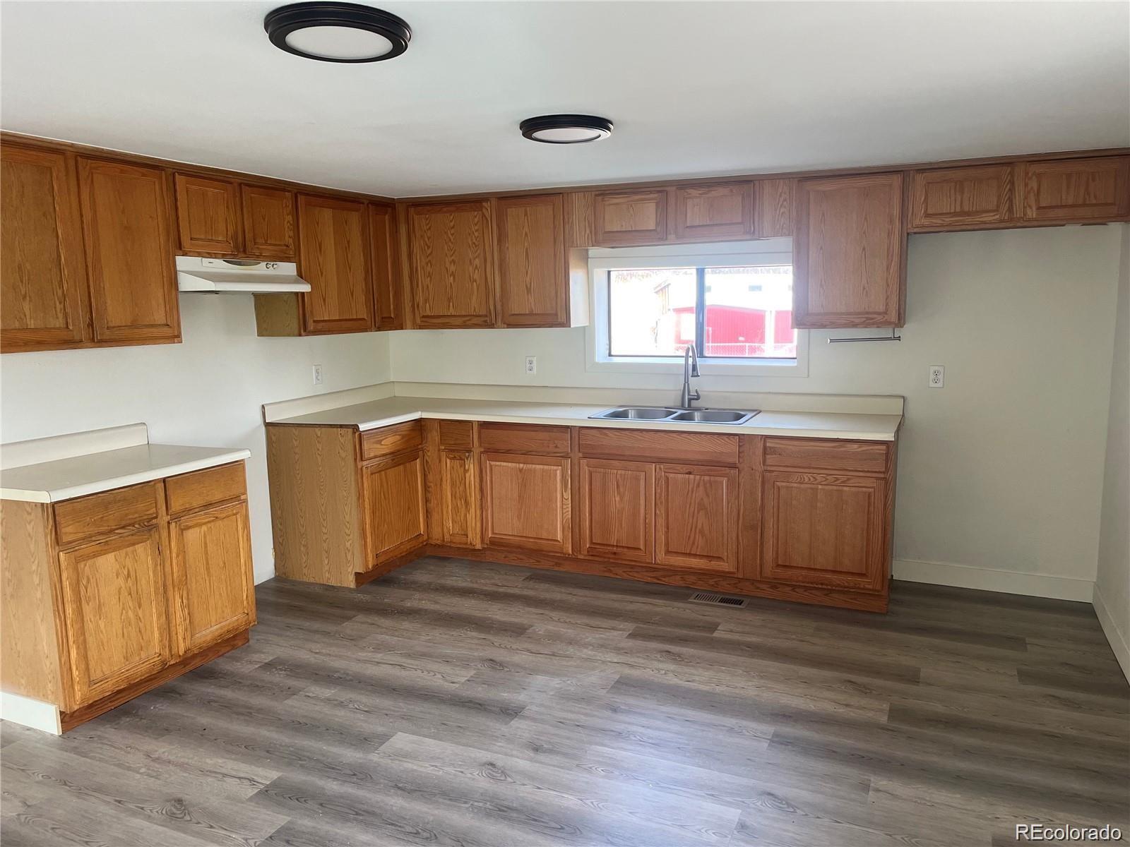 24395 Main Street Elbert, CO 80106 - Photo 4 of 26 a kitchen with granite countertop a sink cabinets and wooden floor