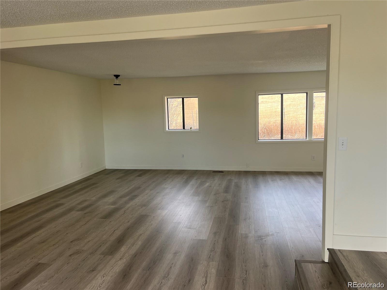 24395 Main Street Elbert, CO 80106 - Photo 5 of 26 an empty room with wooden floor and windows