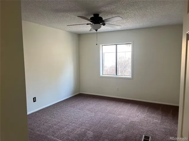 an empty room with a ceiling fan and window