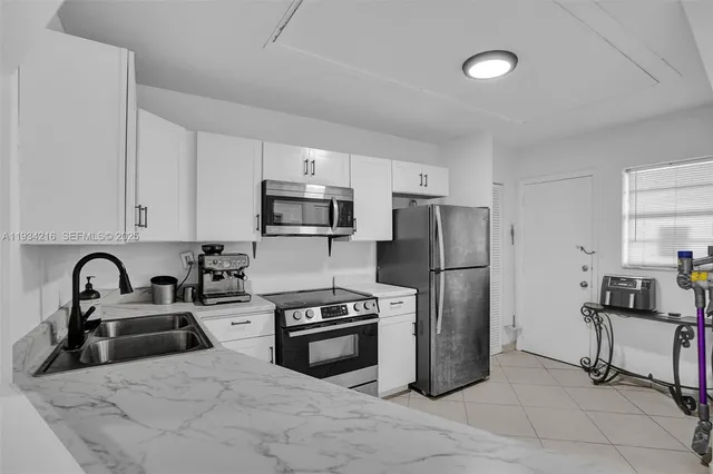 a kitchen with granite countertop a refrigerator and a stove top oven