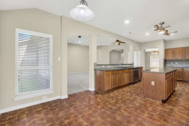 a large kitchen with kitchen island granite countertop a sink cabinets and stainless steel appliances