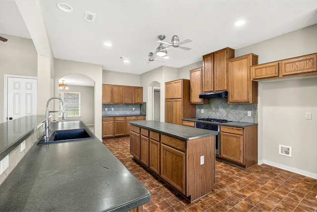 a kitchen with stainless steel appliances granite countertop a sink stove and refrigerator