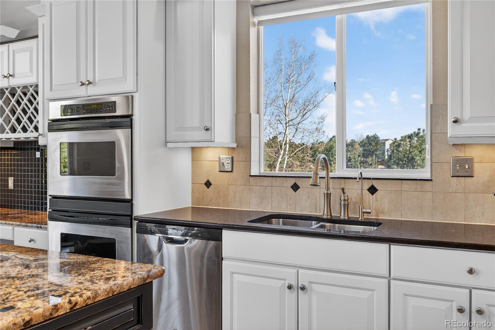 10155 Joseph Drive Highlands Ranch, CO 80124 - Photo 23 of 50 a kitchen with stainless steel appliances granite countertop a sink stove and cabinets