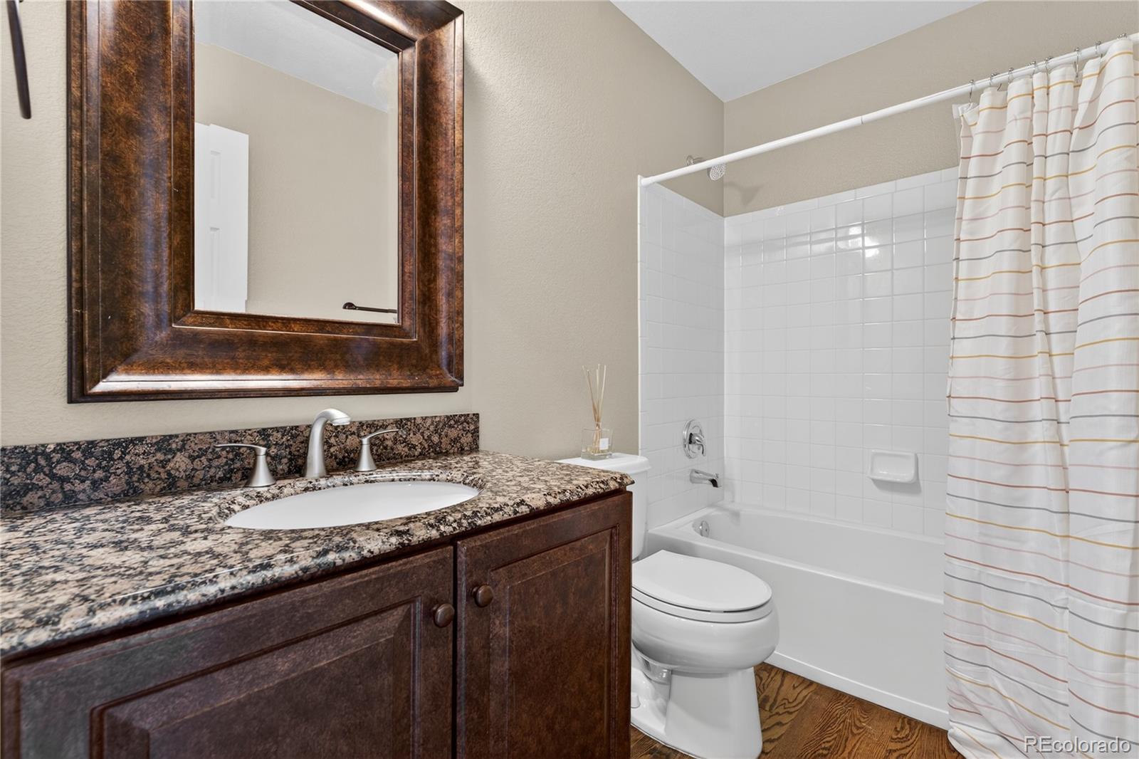 10155 Joseph Drive Highlands Ranch, CO 80124 - Photo 27 of 50 a bathroom with a granite countertop sink toilet a large mirror and shower