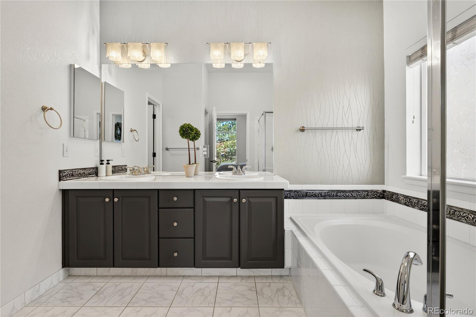 10155 Joseph Drive Highlands Ranch, CO 80124 - Photo 33 of 50 a bathroom with a tub a double vanity sink and a mirror