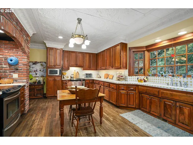 a kitchen with stainless steel appliances granite countertop a stove top oven a sink dishwasher a dining table and chairs with wooden floor