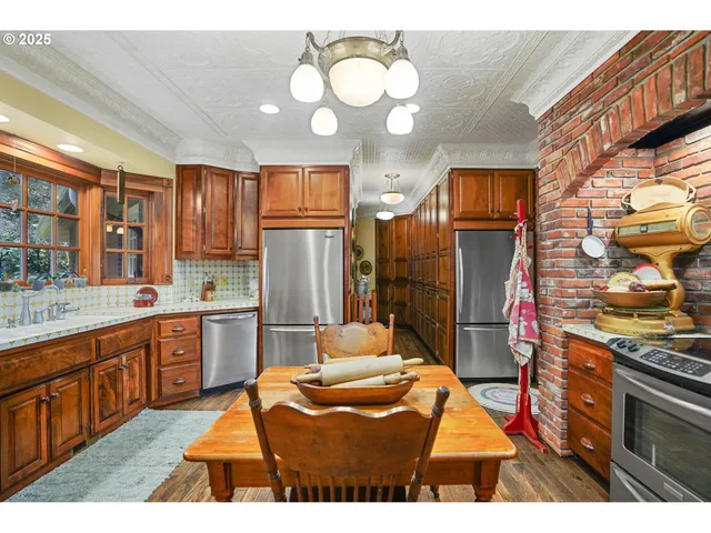 a kitchen with stainless steel appliances kitchen island granite countertop a refrigerator a sink dishwasher and a stove with wooden floor