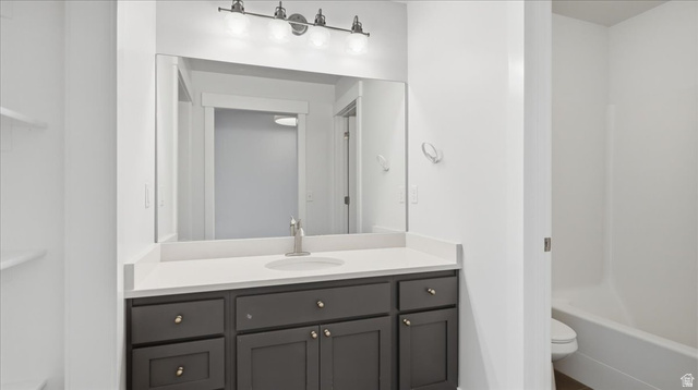 2038 East Ranch Road Eagle Mountain, UT 84005 - Photo 29 of 66 Bathroom vanity featuring a light-toned countertop, undermount sink, and dark cabinetry with brass hardware