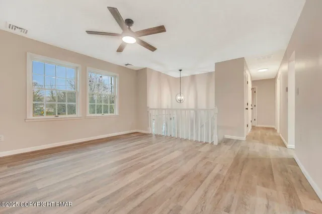 a view of an empty room with a window and wooden floor
