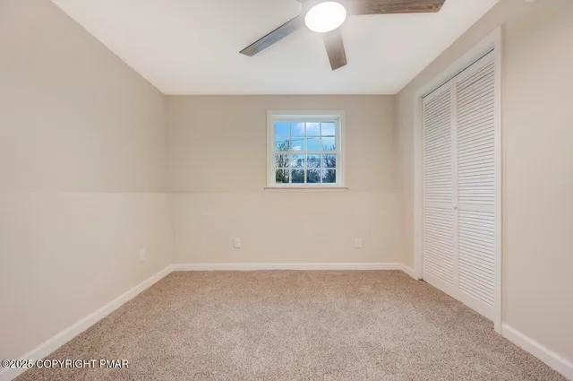 an empty room with wooden floor ceiling fan and windows