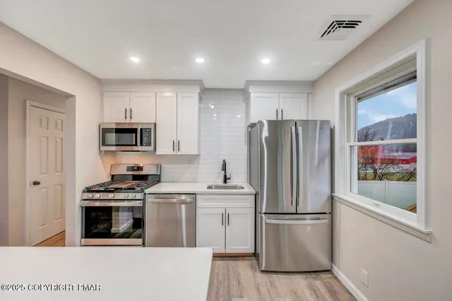 a kitchen with stainless steel appliances a refrigerator sink and microwave