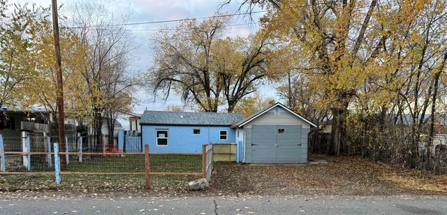 a front view of a house with a yard and large tree