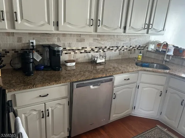 a kitchen with granite countertop stainless steel appliances white cabinets sink and dishwasher
