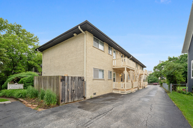 235 East Palatine Road, Unit 1B Palatine, IL 60067 - Photo 1 of 10 a view of a house with wooden fence and large trees